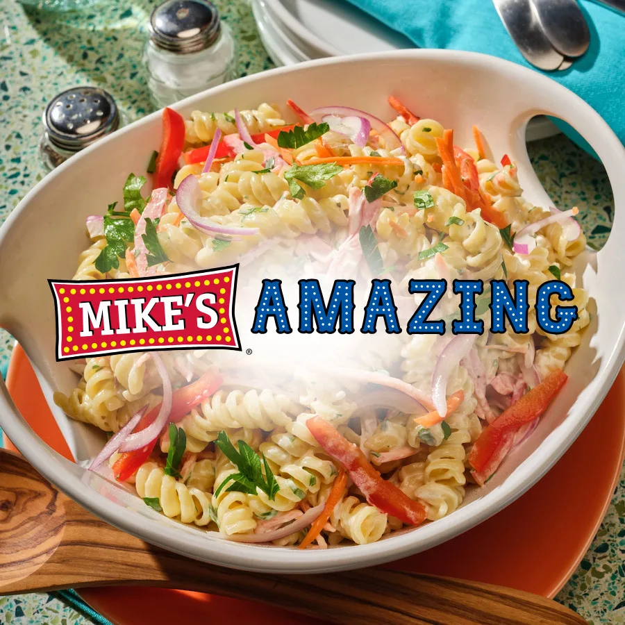 Creamy rotini pasta salad with vegetables and parsley in white bowl by Mike’s Amazing.