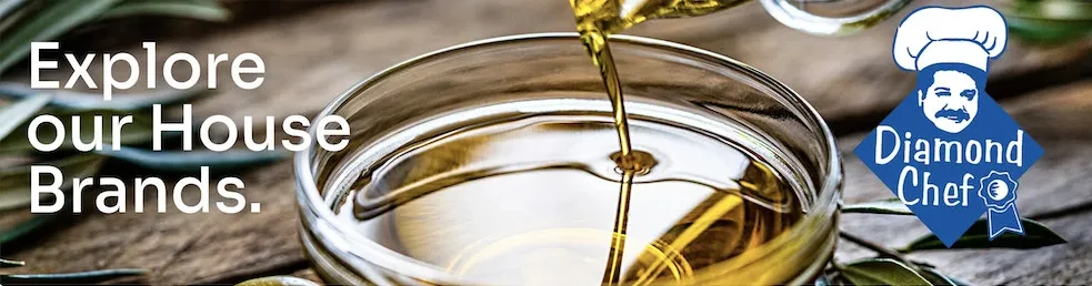 Premium olive oil pouring into a glass bowl, representing Diamond Chef's quality house brand products for food service distributors and wholesale food suppliers.
