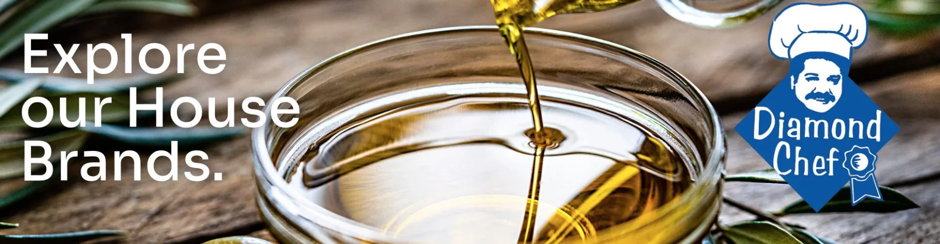Golden olive oil being poured into a glass bowl, representing quality culinary ingredients for food service and wholesale distribution.