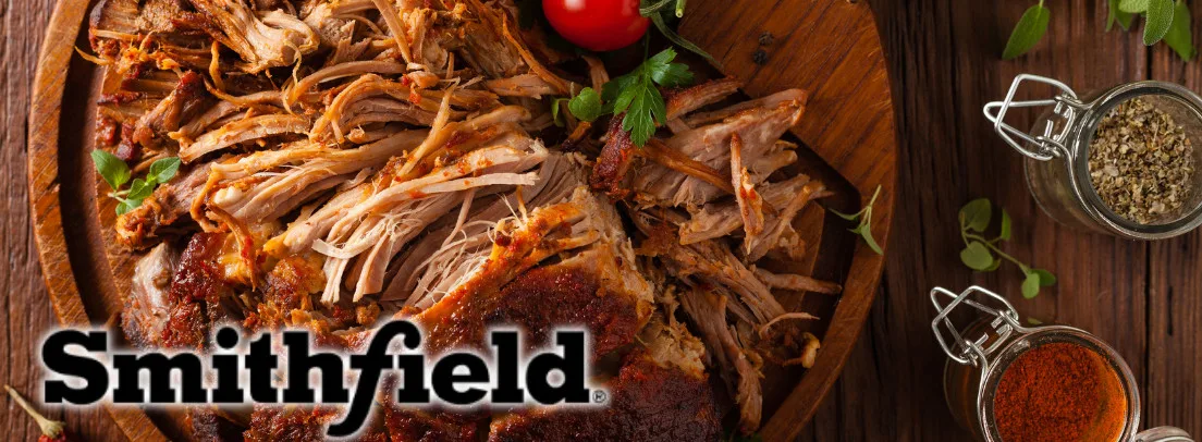 Smithfield branded pulled pork with shredded texture, seasoning blends, and fresh herbs for wholesale food service distribution.